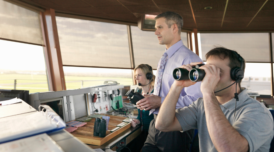Three air traffic controllers check the skyline.