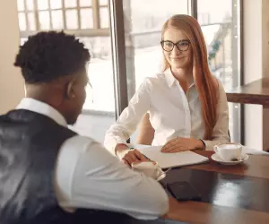 A man and woman sit at a table having an interview