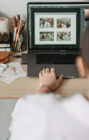 A woman browsing on her laptop at home at her desk with a pen pot next to her