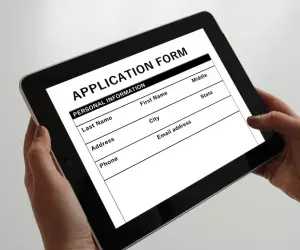a person holding an ipad with an application form on screen