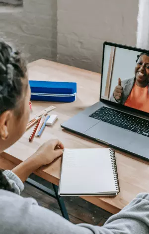 a young girl have a tutoring lesson on her laptop sat at a desk