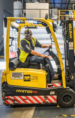 A forklift truck in a warehouse surrounded by stacked boxes and shelves