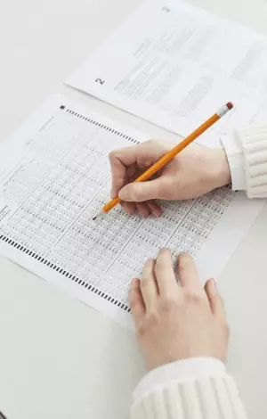 A person filling in a psychometric test with a pencil sat at a table