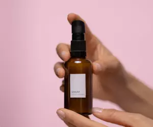 A person holding a product showcasing it against a pink backdrop