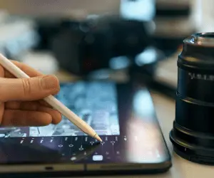 A person using a pen to desing on a tablet, showing graphic design