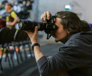 A press photographer using a camera to take a photograph