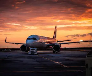 A large jet airplane parked on the runway at sunset