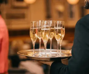 A waiter holding a tray of full glasses in a restaurant setting
