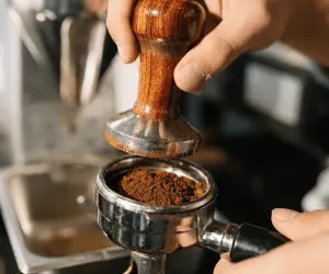 A barista grinding coffee beans ready to go into a coffee machine