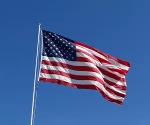 An American flag waving in the wind with a bright blue sky in the background