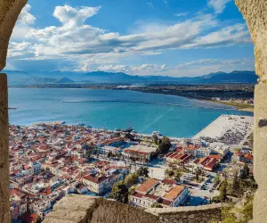 Looking through a stone arch, highlighting the city and its natural surroundings in Greece