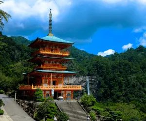 A serene mountain pagoda with a winding path leading up to it, surrounded by lush greenery and distant peaks