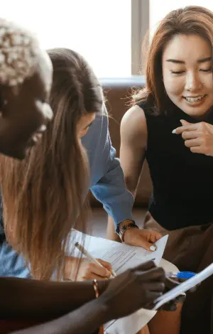 three females sat next to each other looking at a board discussing ideas