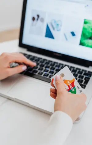 A close up of a person sat with their laptop, holding their bank card doing online banking