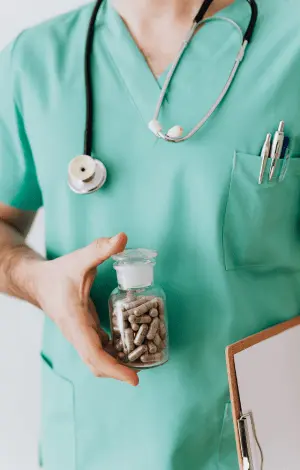 A healthcare professional wearing a blue coat, displays a jar of pills, ready to discuss with a patient