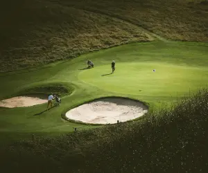 A scenic golf course with several players engaged in a game under clear blue skies