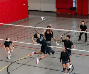 A group of people playing volleyball in an indoor gym