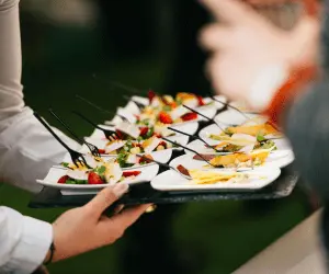 A waiter serving canopies to guests at an event