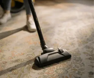 A close up of a person hoovering a carpet