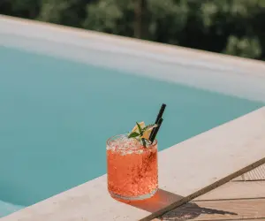 A refreshing drink resting next to a crystal clear blue pool