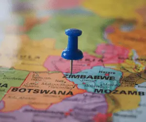 A close up of a map with a blue pin in the location of Zimbabwe