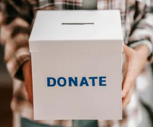 A close up of a person holding a donations box