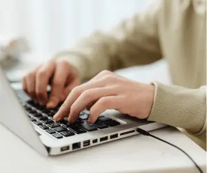 A close up of a person typing on their laptop
